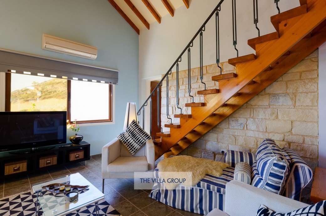 Wooden staircase leads to a sloped ceiling sleeping area on the mezzanine level furnished with two single beds and a separate wc