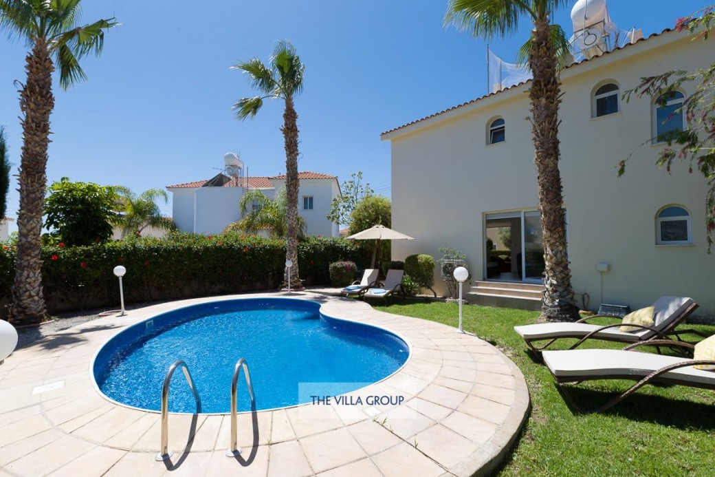 Swimming pool is surrounded by established gardens and a paved sunbathing terrace