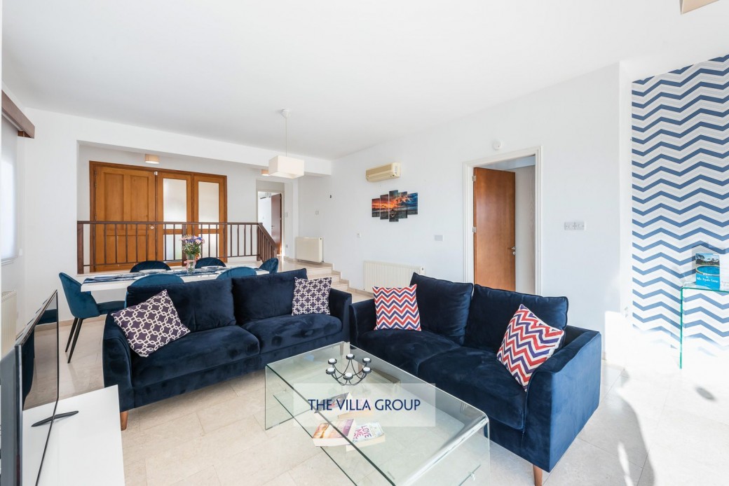 The room is bright and warm with large patio doors opening out onto the outdoor furnished terrace area and swimming pool