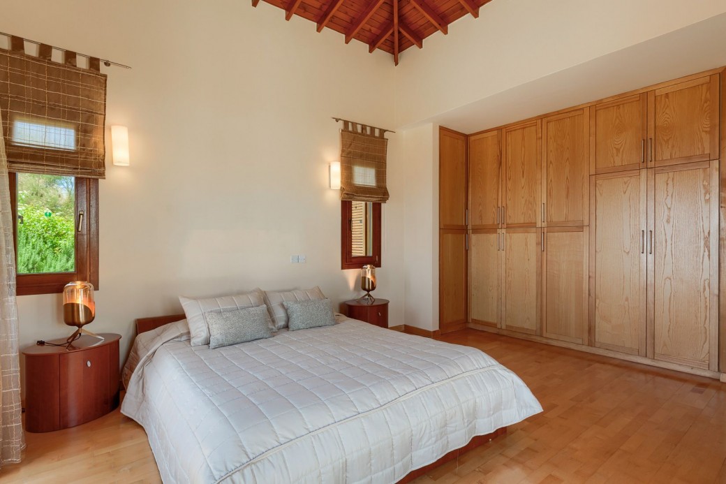 The room comprises a king-size bed, bedside tables with matching lamps, spacious wardrobes