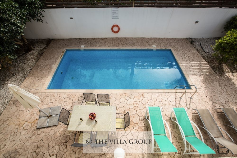 Swimmin pool area with outside table and sun loungers