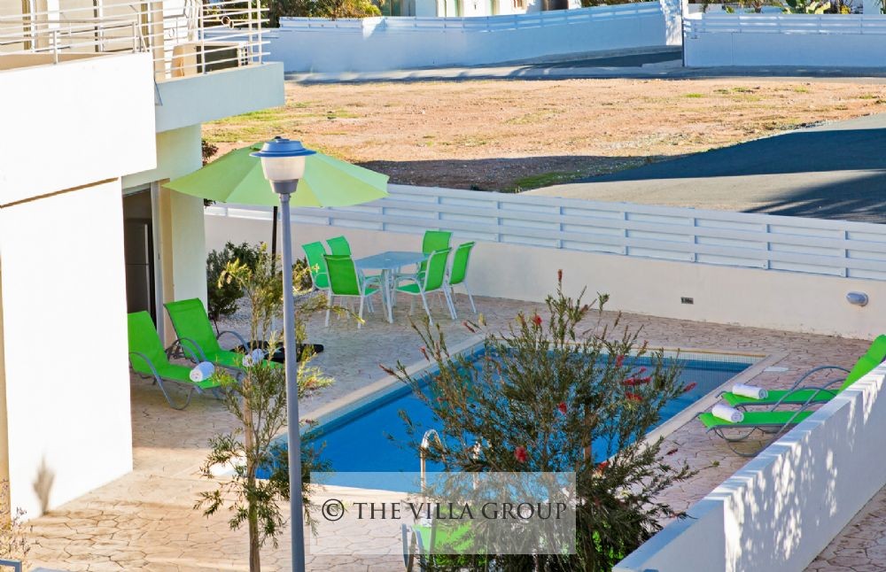 Swimming pool surrounded by sun loungers and patio table