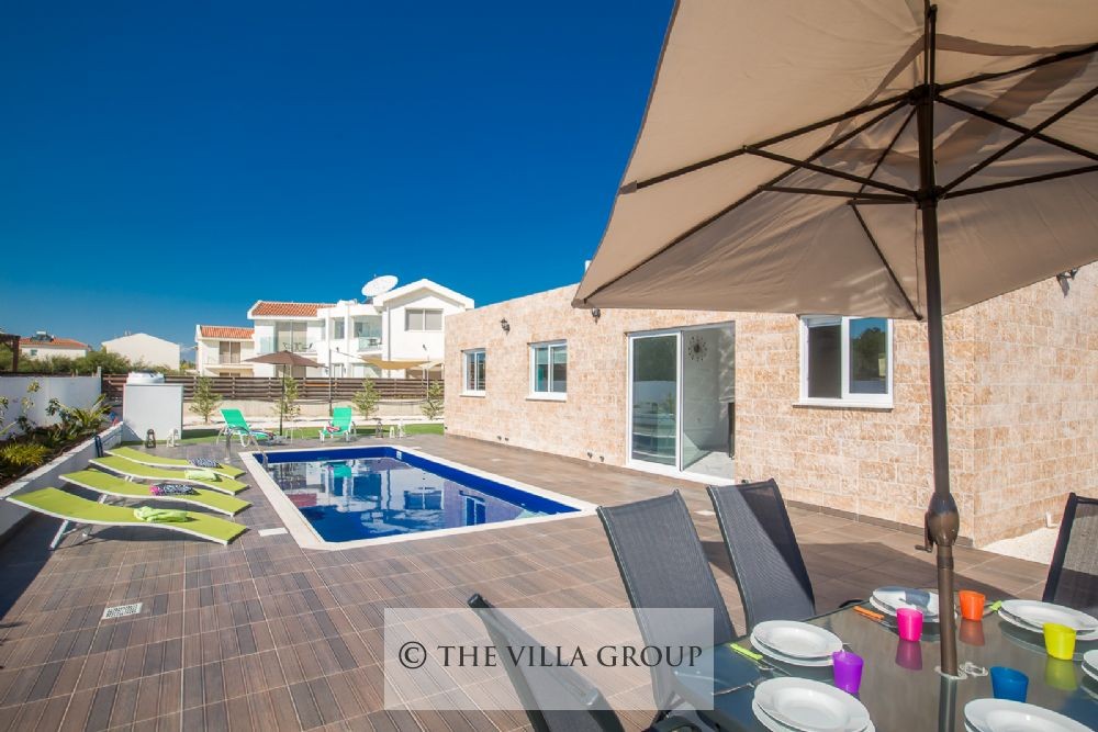Swimming pool surrounded by sun loungers with an outside dining table