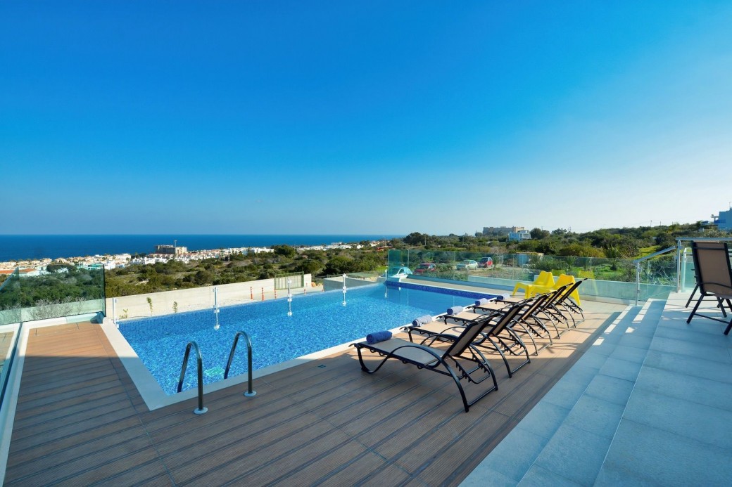 Overflow swimming pool surrounded by sunbeds for relaxing under the Cyprus sunshine
